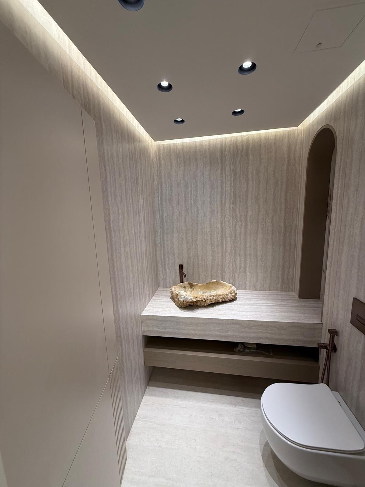 Travertine WC with a stone basin on a floating shelf
