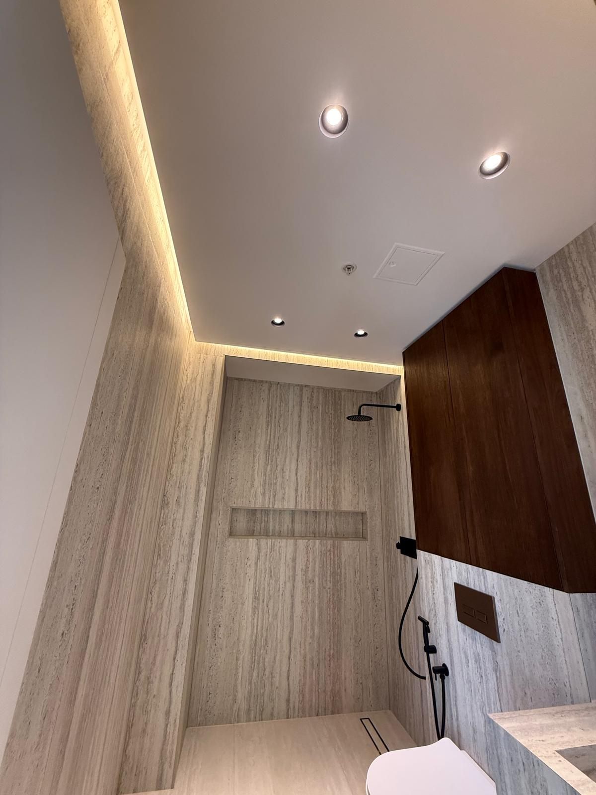 Walk-in shower with a travertine niche and walnut panel