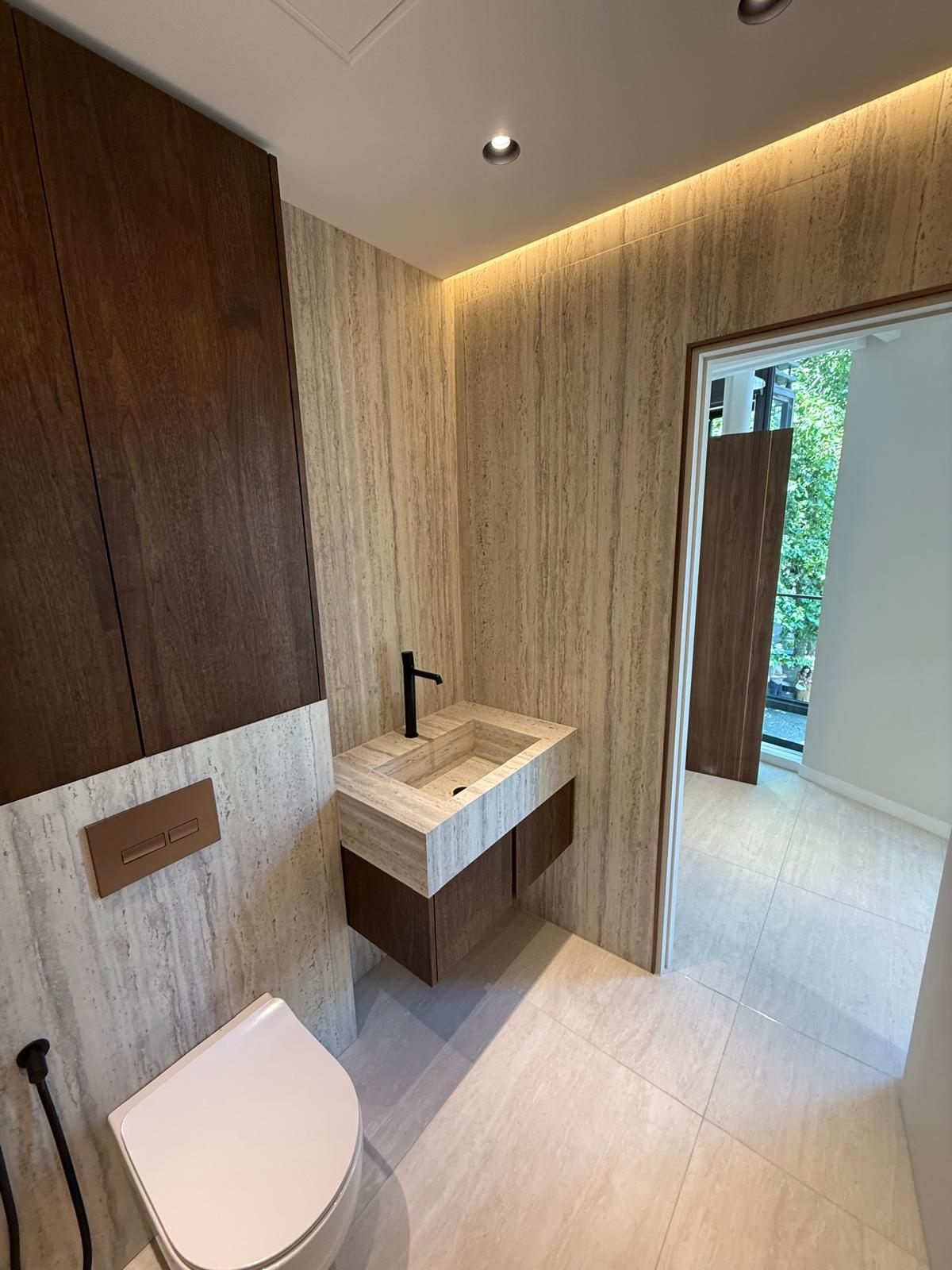 Walnut vanity and wall-hung WC under a warm LED cove