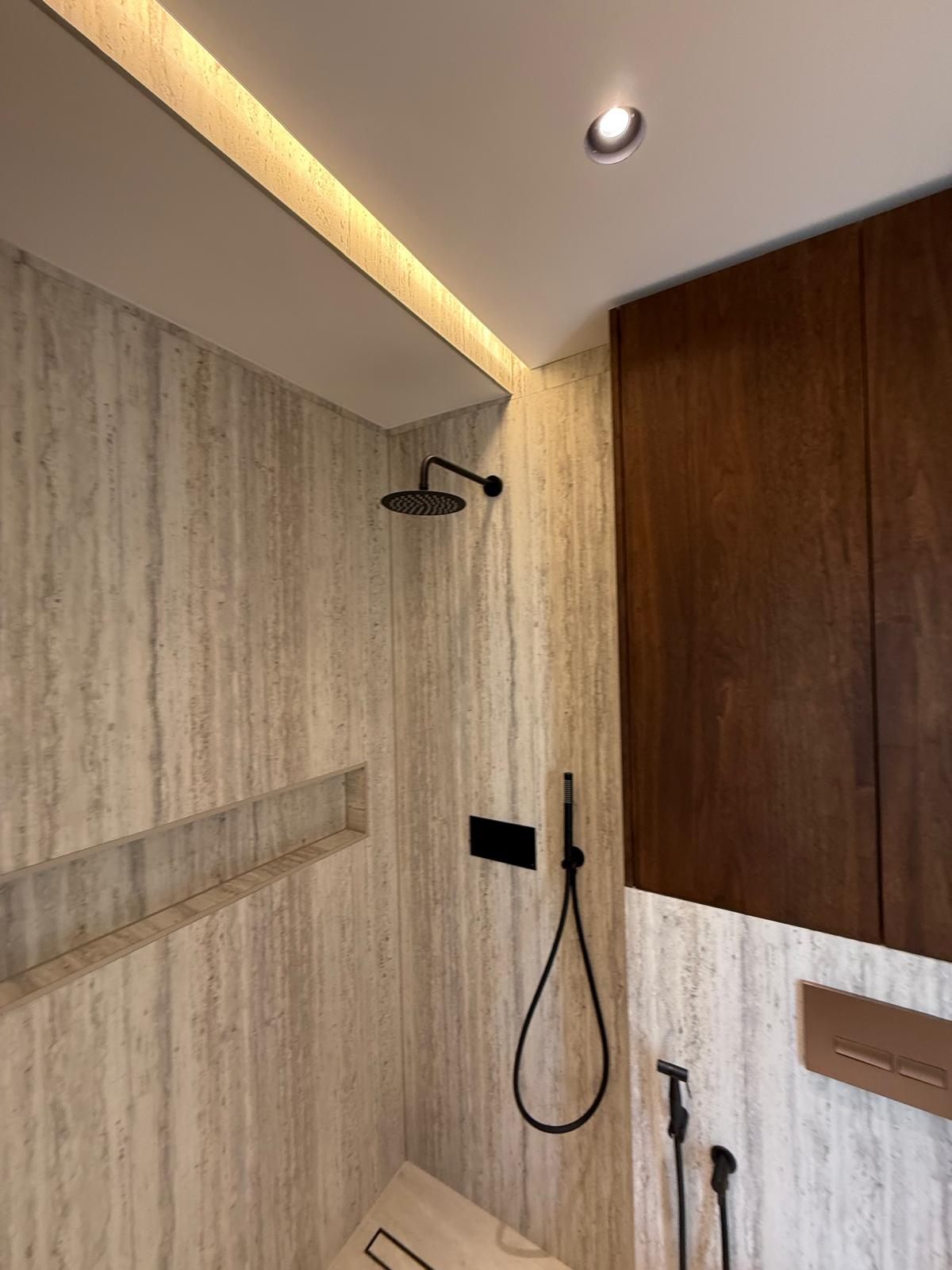 Travertine shower wall with a long recessed niche