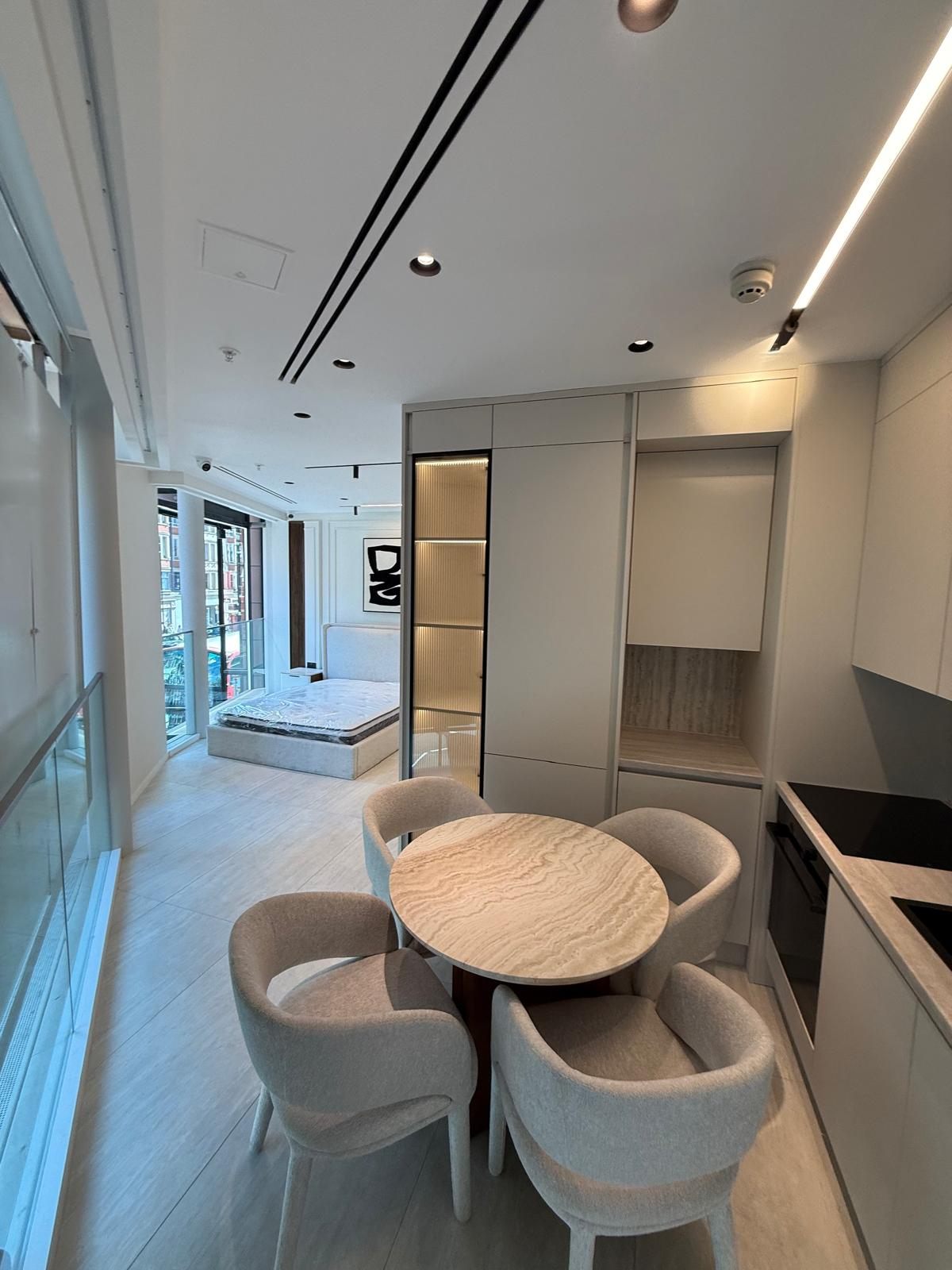 Handle-less kitchen and dining table in an open-plan studio